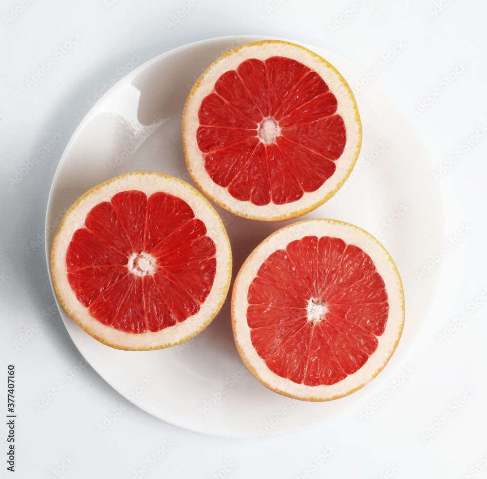 Fresh Red Grapefruits on a white plate. White background. Top view Fresh Red Grapefruits on a white plate. White background. Top view