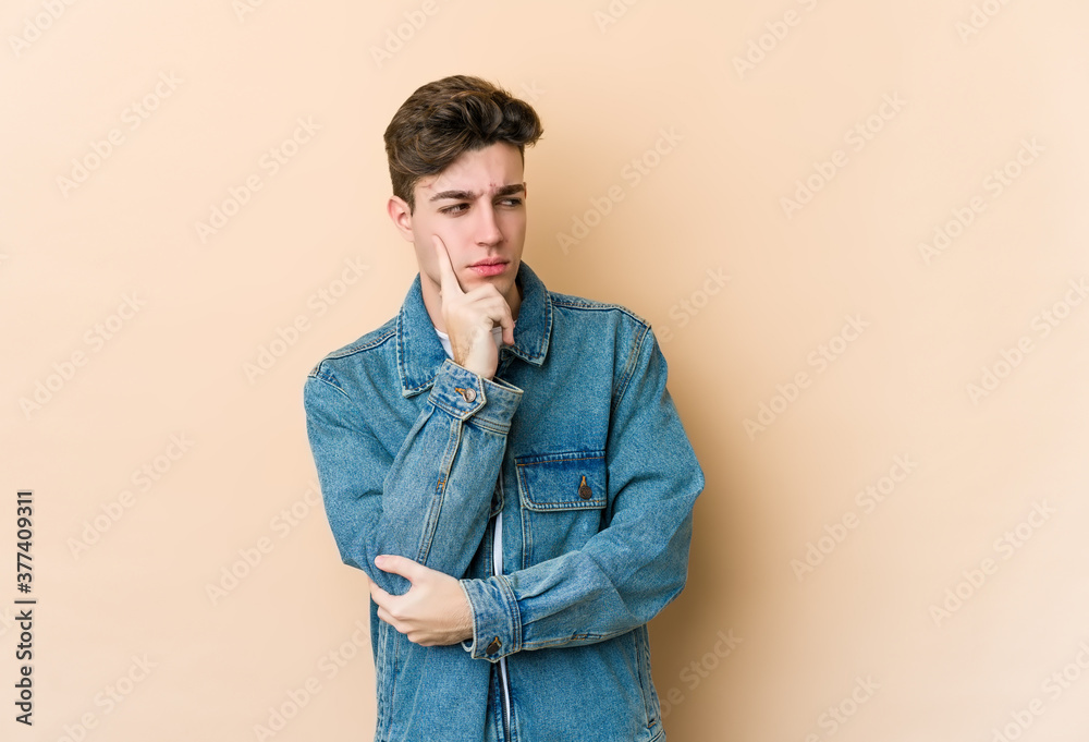Young caucasian man isolated on beige background contemplating, planning a strategy, thinking about the way of a business. Young caucasian man isolated on beige background contemplating, planning a strategy, thinking about the way of a business.