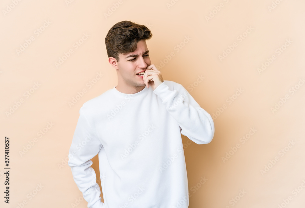 Young caucasian man isolated on beige background relaxed thinking about something looking at a copy space. Young caucasian man isolated on beige background relaxed thinking about something looking at a copy space.