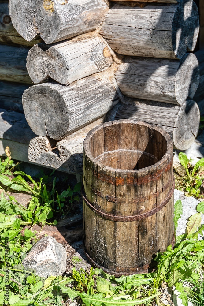 Old oak tub in the corner of a wooden old house as a vintage background.