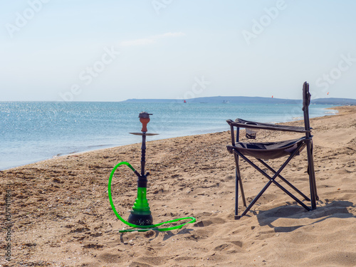 Hookah and camping chair on the sandy beach by sea. Rest and relax in the wild in summer, at sea shore chilling out and relaxing