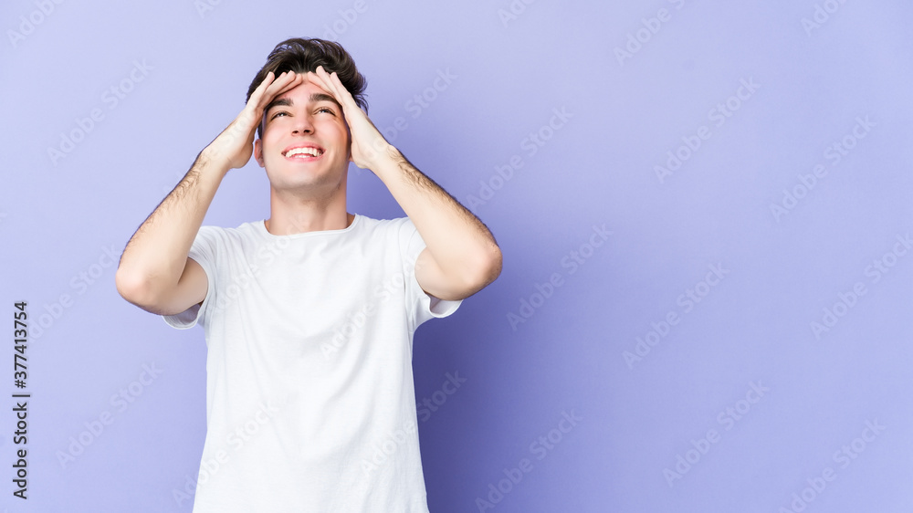 Young caucasian man isolated on purple background laughs joyfully keeping hands on head. Happiness concept. Young caucasian man isolated on purple background laughs joyfully keeping hands on head. Happiness concept.