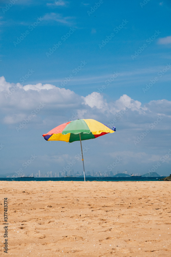 Beach umbrella on the beach with a city skyline in the background Beach umbrella on the beach with a city skyline in the background