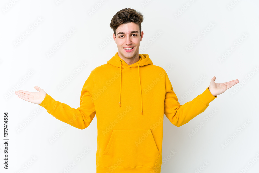 Young caucasian man isolated on white background makes scale with arms, feels happy and confident. Young caucasian man isolated on white background makes scale with arms, feels happy and confident.