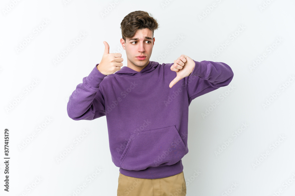 Young caucasian man isolated on white background showing thumbs up and thumbs down, difficult choose concept Young caucasian man isolated on white background showing thumbs up and thumbs down, difficult choose concept