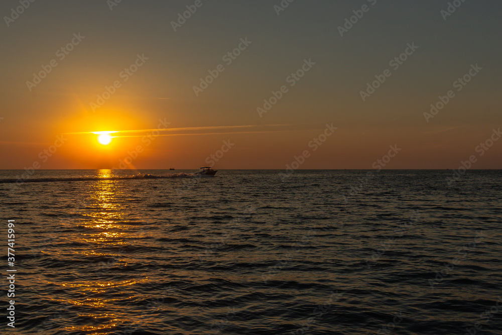 boat rushes through the sea during sunset. city of Sochi.