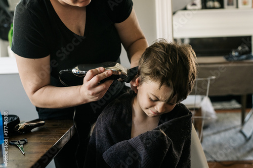 Boy expresses displeasure with having his mother clipper his hair photo