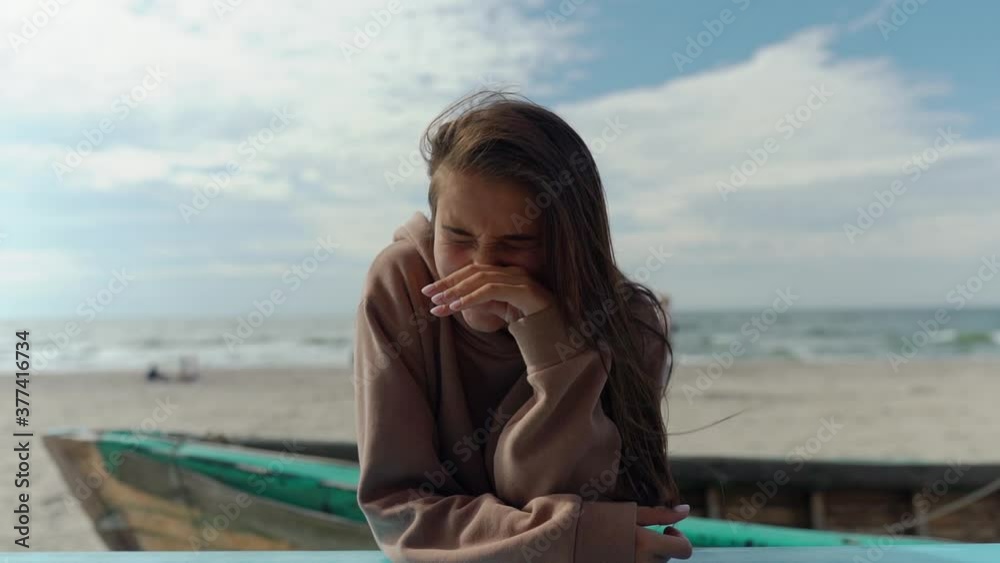 Happy young woman relax on beach bar and looking away while laughing. Autumn, seaside, outdoor, vacation, travel Happy young woman relax on beach bar and looking away while laughing. Autumn, seaside, outdoor, vacation, travel