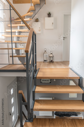 Staircase of a private house with modern stairs. Steel frame with wooden steps, white and gray walls, harmonious color concept. Vertical stock photo.