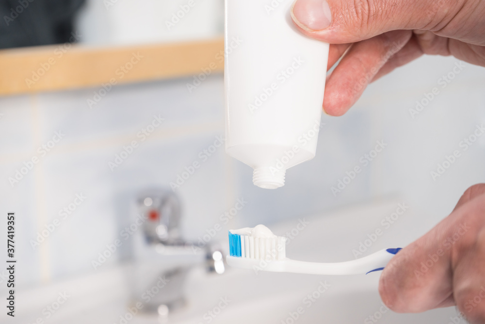 Person putting toothpaste on toothbrush Person putting toothpaste on toothbrush