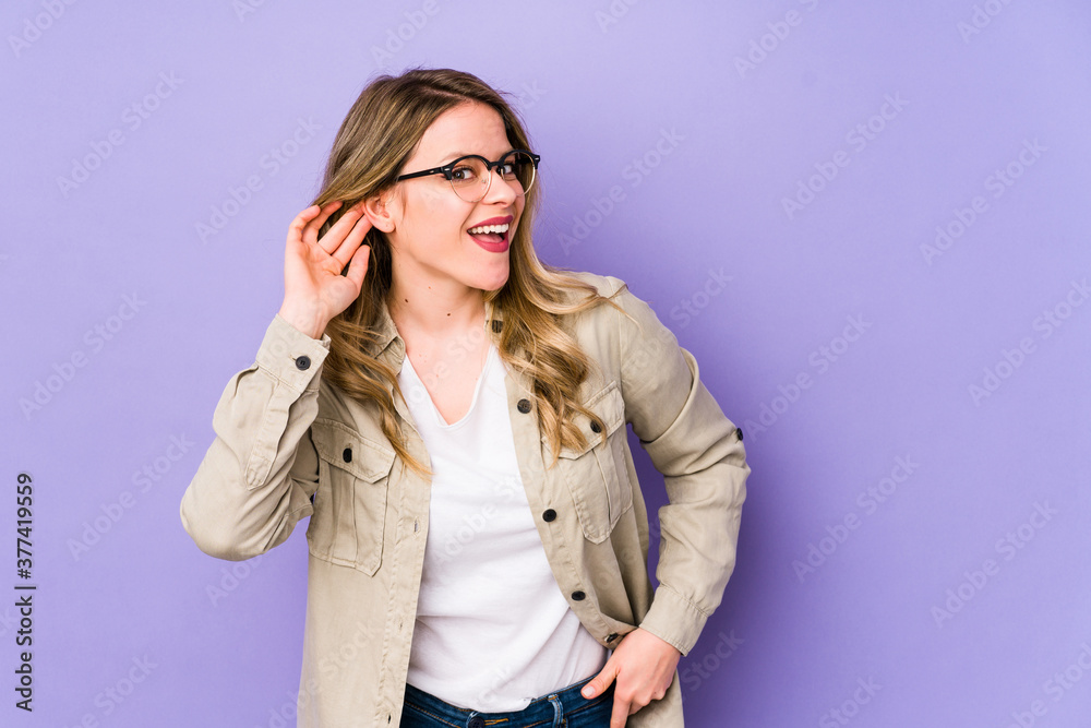 Young caucasian woman isolated on purple background trying to listening a gossip. Young caucasian woman isolated on purple background trying to listening a gossip.