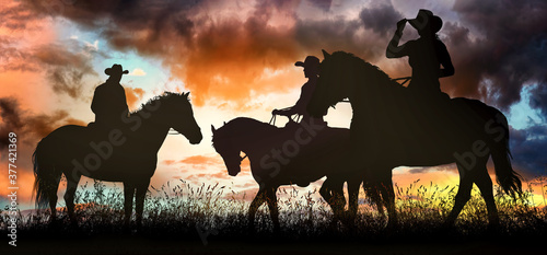 Fototapeta Naklejka Na Ścianę i Meble -  Three cowboys at sunset