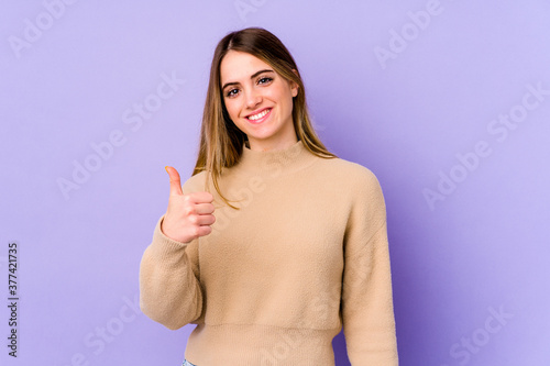 Young caucasian woman isolated on purple background smiling and raising thumb up