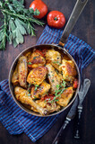 Traditional French lemon chicken in sauce with tomatoes offered as top view in a rustic casserole