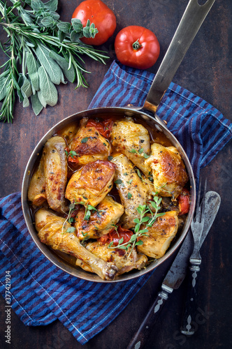 Traditional French lemon chicken in sauce with tomatoes offered as top view in a rustic casserole