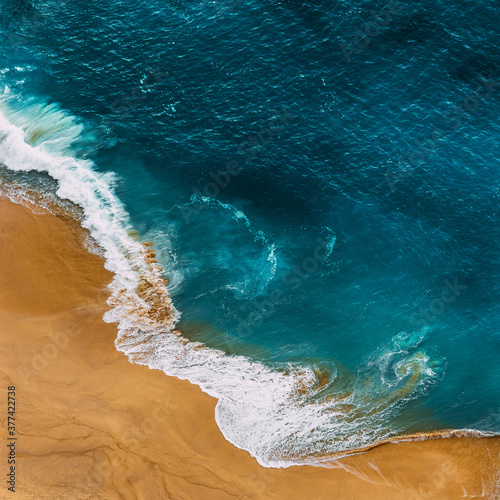 Clean sandy beach with yellow sand and blue sea, vertical photo. Aerial photography of a clean sandy beach. Beautiful beach with yellow sand. Aerial photography of the seascape. Instagram format