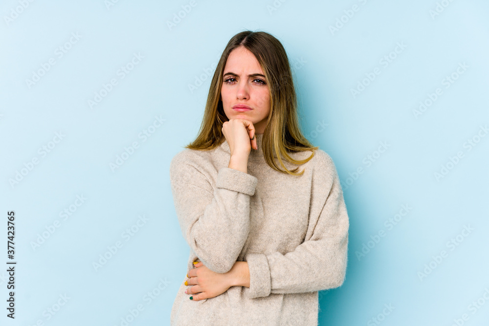 Young caucasian woman isolated on blue background suspicious, uncertain, examining you. Young caucasian woman isolated on blue background suspicious, uncertain, examining you.