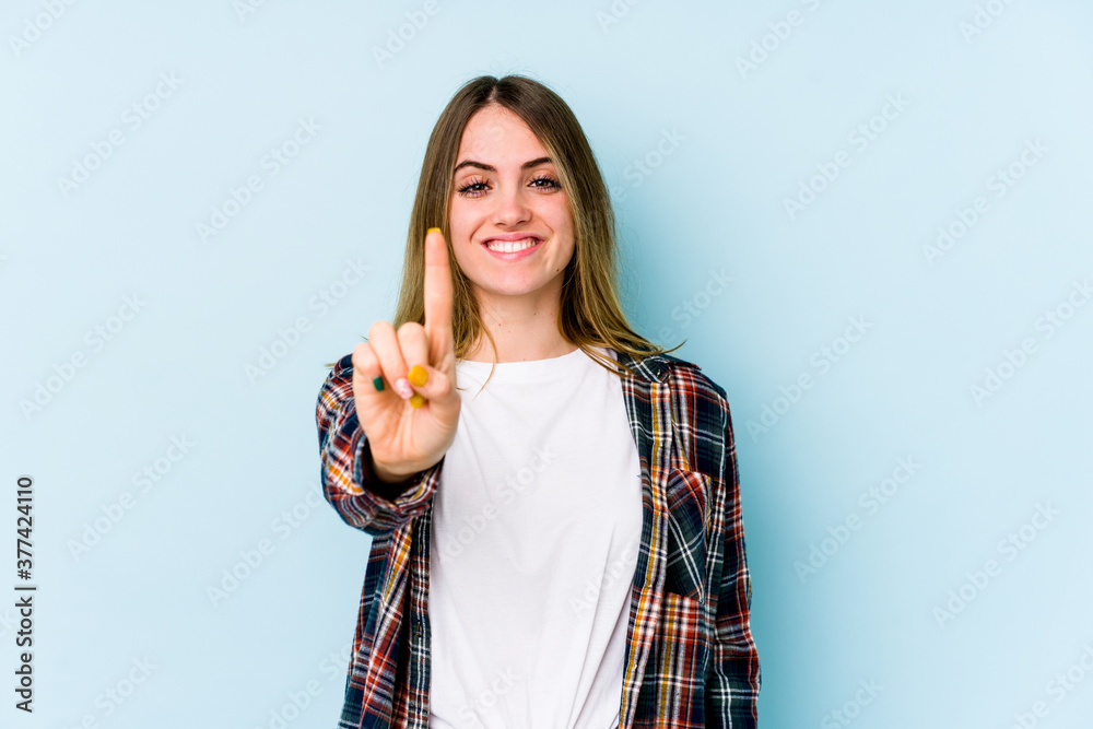 Young caucasian woman isolated on blue background showing number one with finger. Young caucasian woman isolated on blue background showing number one with finger.