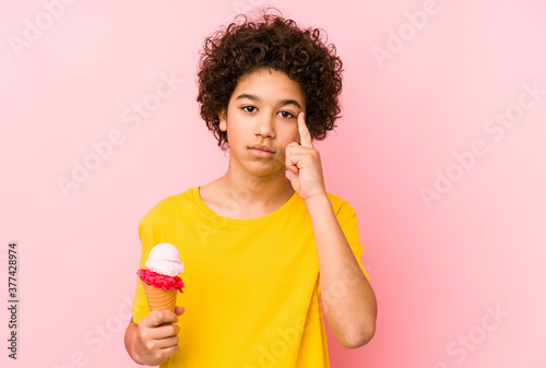 Kid boy holding an ice cream isolated pointing temple with finger, thinking, focused on a task.