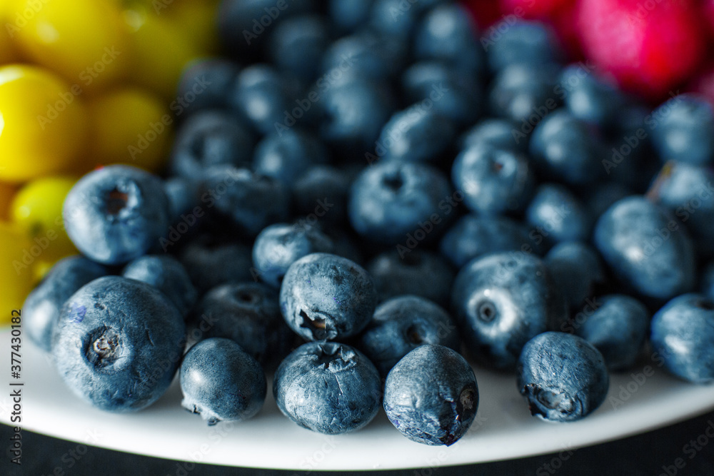 View from above. A mix of yellow, red and blue berries in a white grater. Triangle separation. Summer mix of fruits. Berry layout View from above. A mix of yellow, red and blue berries in a white grater. Triangle separation. Summer mix of fruits. Berry layout
