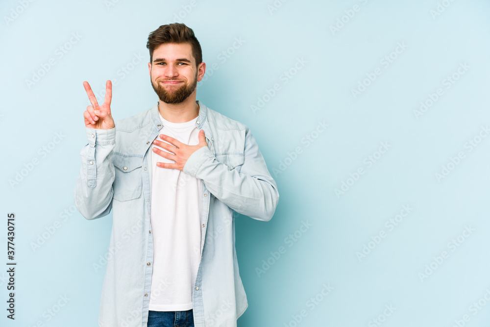 Young caucasian man isolated on blue background taking an oath, putting hand on chest. Young caucasian man isolated on blue background taking an oath, putting hand on chest.