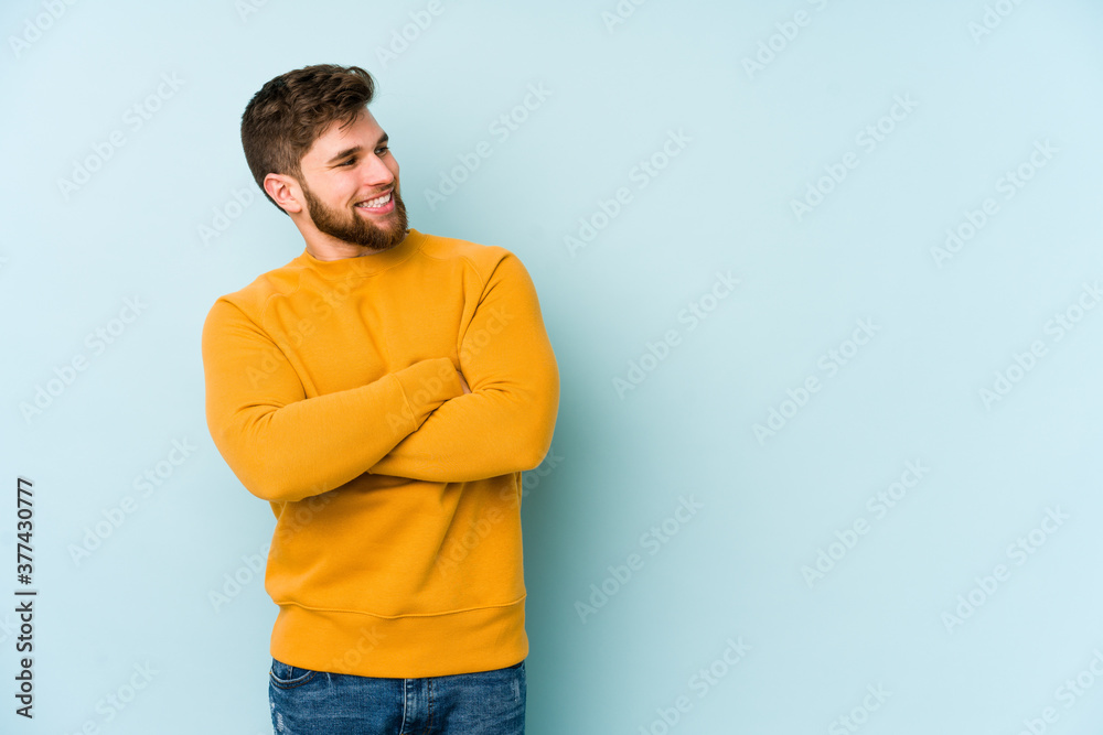 Young caucasian man isolated on blue background smiling confident with crossed arms. Young caucasian man isolated on blue background smiling confident with crossed arms.