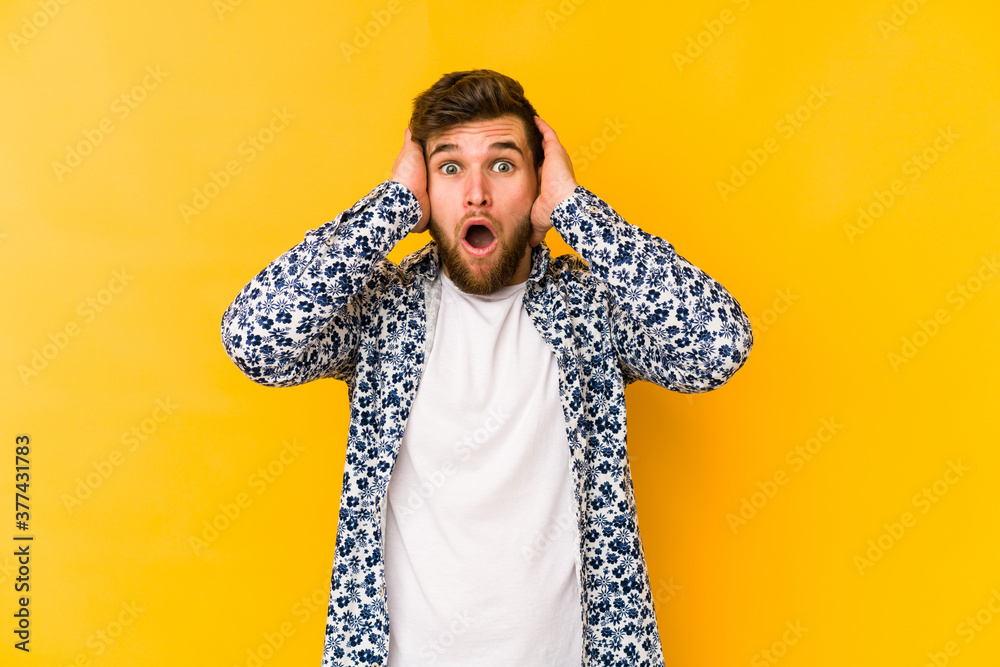 Young caucasian man isolated on yellow background being shocked, she has remembered important meeting. - obrazy, fototapety, plakaty 