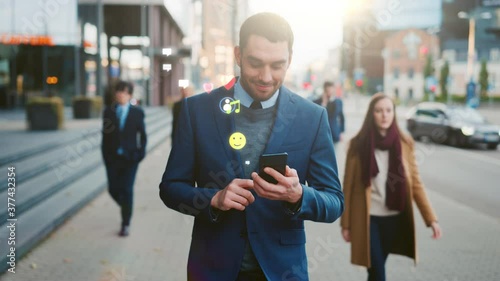 Beautiful Young Woman Uses Smartphone with Animated Social Media Icons Flying Away, Walks on Crowded City Streets. Social Network Concept, Likes, Emoticons, e-business. Front View Following Shot  photo