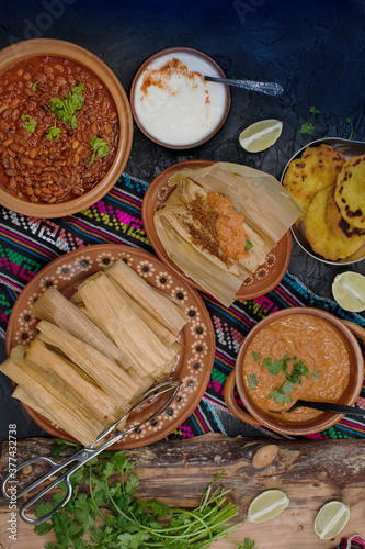 Vegan tamales filled with seitan, masa, chile verde and served with ranchero sauce, cream and chili beans in a traditional Mexican setting