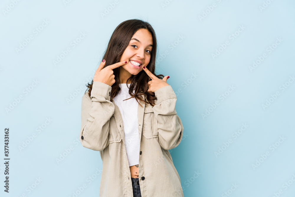 Young mixed race hispanic woman isolated smiles, pointing fingers at mouth. Young mixed race hispanic woman isolated smiles, pointing fingers at mouth.