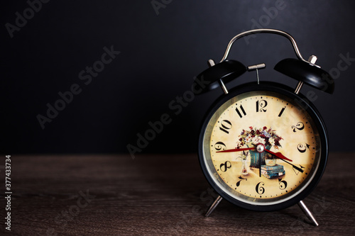 Retro Black Paint Metal Alarm Clock On Wooden Table And Black Wall Background