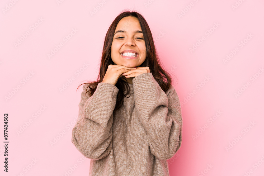 Young mixed race hispanic woman isolated keeps hands under chin, is looking happily aside.