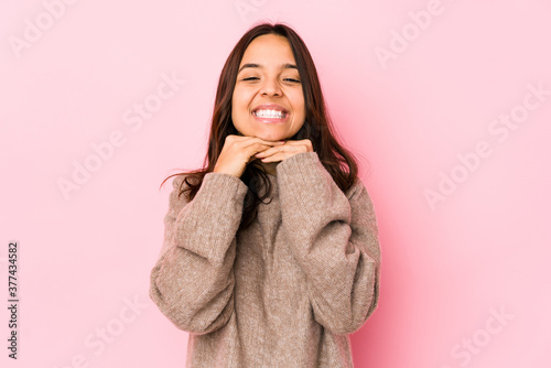 Young mixed race hispanic woman isolated keeps hands under chin, is looking happily aside.
