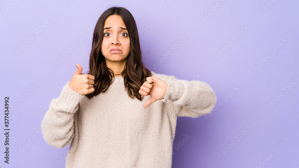 Young mixed race hispanic woman isolated showing thumbs up and thumbs down, difficult choose concept Young mixed race hispanic woman isolated showing thumbs up and thumbs down, difficult choose concept