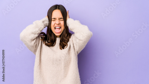 Young mixed race hispanic woman isolated covering ears with hands trying not to hear too loud sound. © Asier