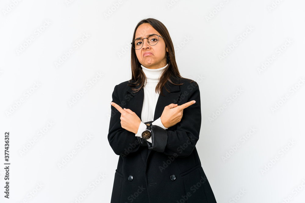 Young mixed race business woman isolated on white background points sideways, is trying to choose between two options. Young mixed race business woman isolated on white background points sideways, is trying to choose between two options.