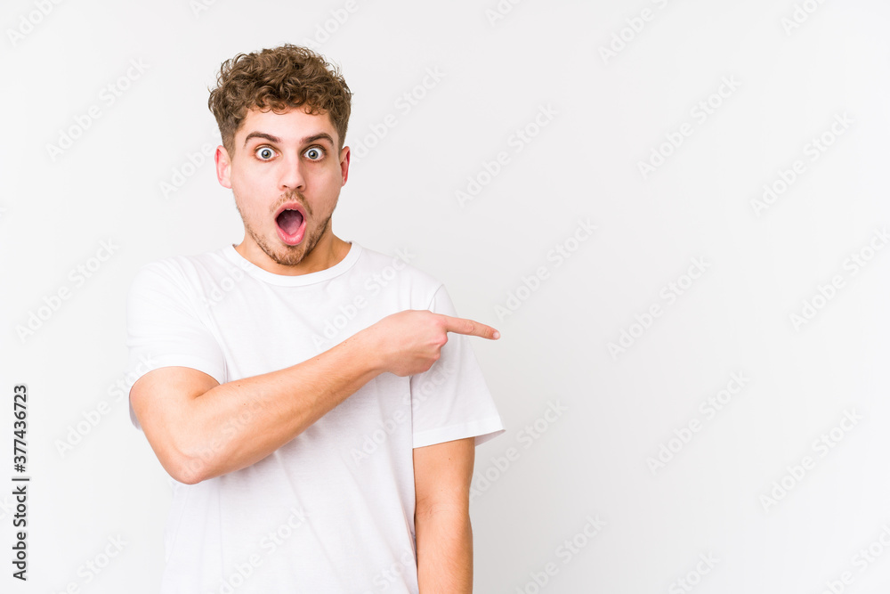 Young blond curly hair caucasian man isolated pointing to the side Young blond curly hair caucasian man isolated pointing to the side