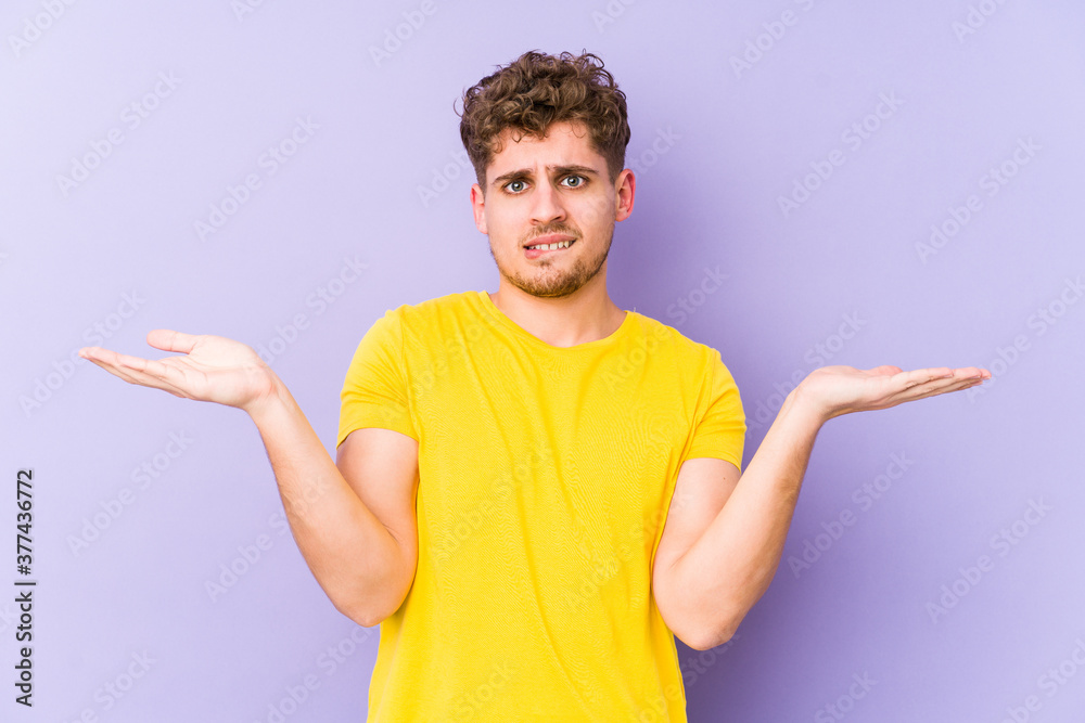 Young blond curly hair caucasian man isolated confused and doubtful shrugging shoulders to hold a copy space. Young blond curly hair caucasian man isolated confused and doubtful shrugging shoulders to hold a copy space.
