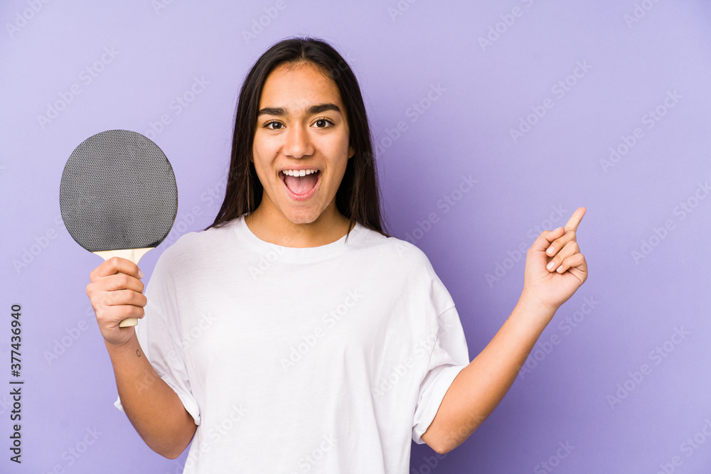 Young indian woman playing ping pong isolated smiling cheerfully pointing with forefinger away. Young indian woman playing ping pong isolated smiling cheerfully pointing with forefinger away.