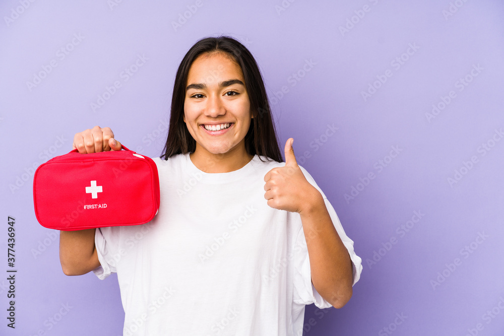 Young indian woman holding an aid kid isolated smiling and raising thumb up Young indian woman holding an aid kid isolated smiling and raising thumb up