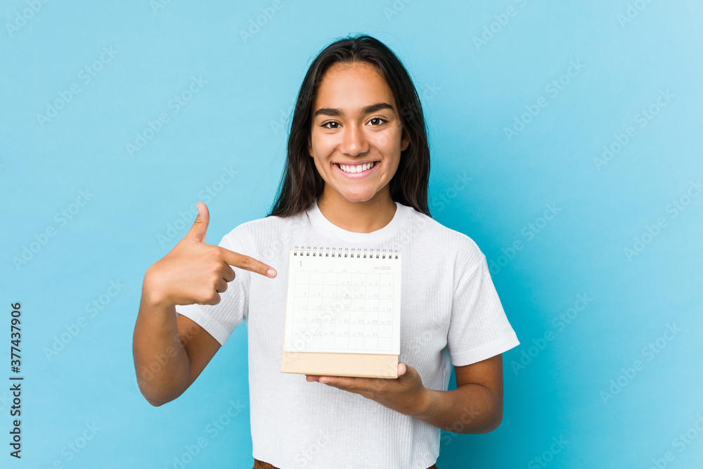 Young indian woman happy holding a calendar isolated Young indian woman happy holding a calendar isolated