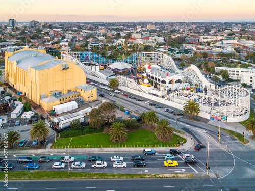 Aerial view of cars stopped at city intersection near a large hall and an amusement park