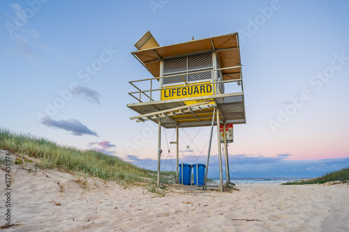 Looking up at a deserted lifeguards tower on a sandy track at twilight photo