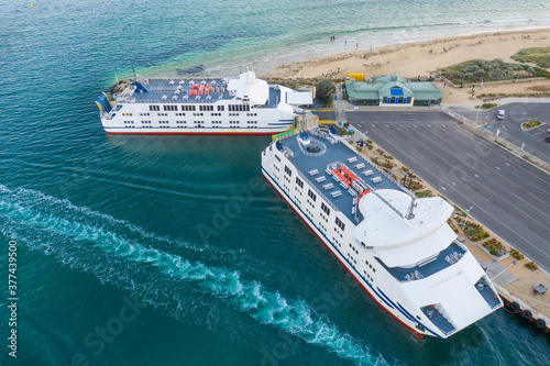 Two car ferries anchored at a terminal near a beach photo