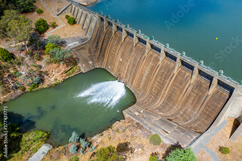 Looking down on a jet of water squirting from the bottom of a dam wall of a reservoir photo