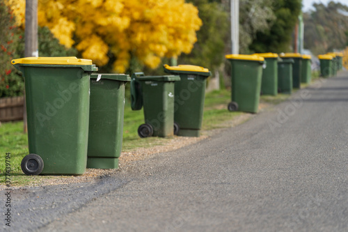 A row of wheelie bins along the side of a bitumen road photo