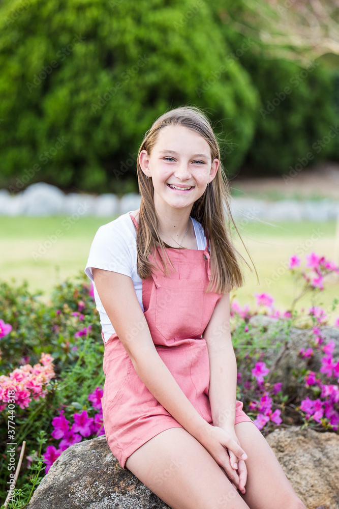 Young girl sitting on rock in garden smiling happy Young girl sitting on rock in garden smiling happy