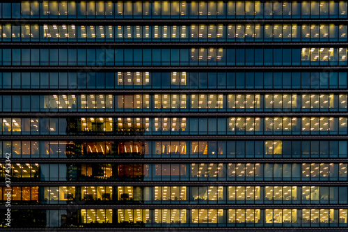 Photography wall background of tower glass exterior facade with interior yellow lighting glow in each floor