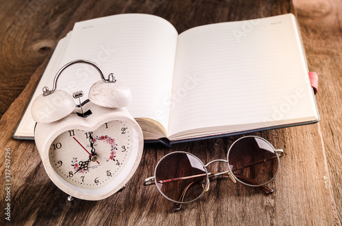 Book and clock glasses on grunge wood background illustrate to vacation concept