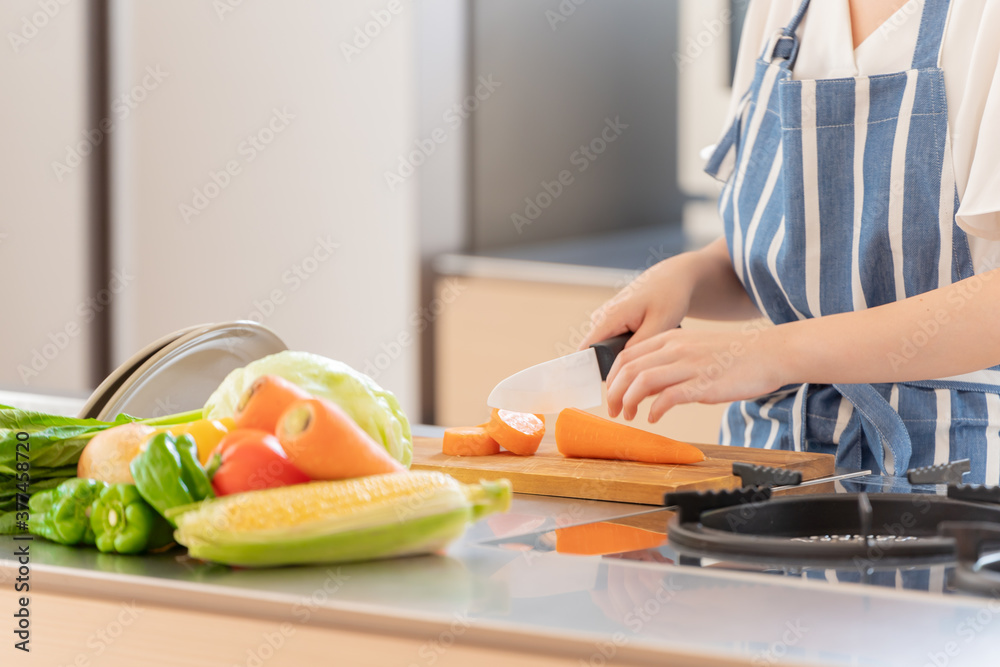 Obraz premium キッチンでにんじんを切る女性